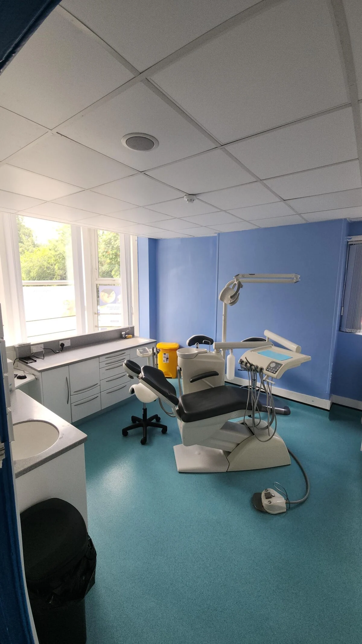 Twilight Dental treatment room with dental chair, calming light-blue walls and window view